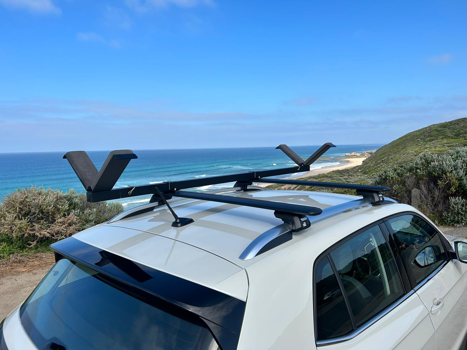 Car with Vrack installed on roof rack, with blue skies and beach background