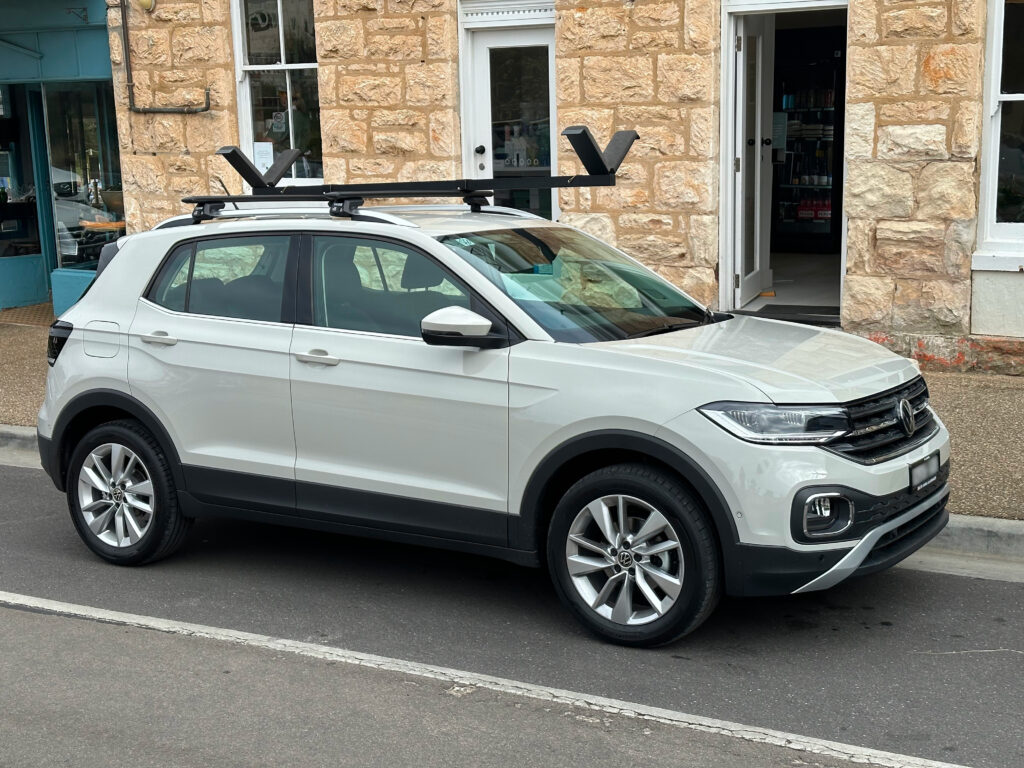White car with Vrack installed on roof rack and parked on street